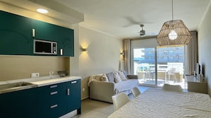 Una cocina moderna con armarios color turquesa, un microondas y un comedor con mesa y sillas.