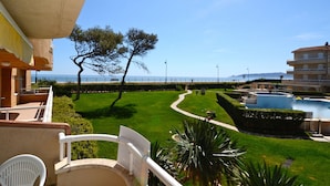Varanda com vista para um jardim paisagístico, uma piscina e um edifício com varandas.