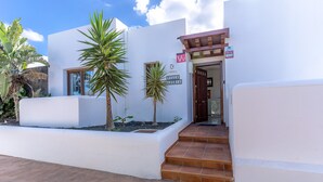 Een moderne villa met een witte gevel, een houten deur en een bordje dat aangeeft dat het een villa is.
