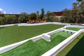 Un parcours de golf doté d’une pelouse artificielle, de lignes de démarcation blanches et de différentes espèces de plantes.