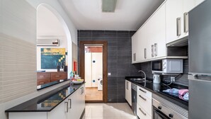 Een moderne keuken met witte kasten, een zwart aanrecht en roestvrijstalen apparatuur.