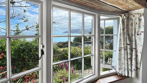 A room with a large bay window overlooking a garden and the sea. - The Crows Nest, Porlock Weir (Somerset)