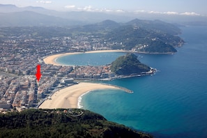 An aerial view of a coastal city with a beach, a peninsula, and a dense urban area. - Colon by FeelFree Rentals (San Sebastián)