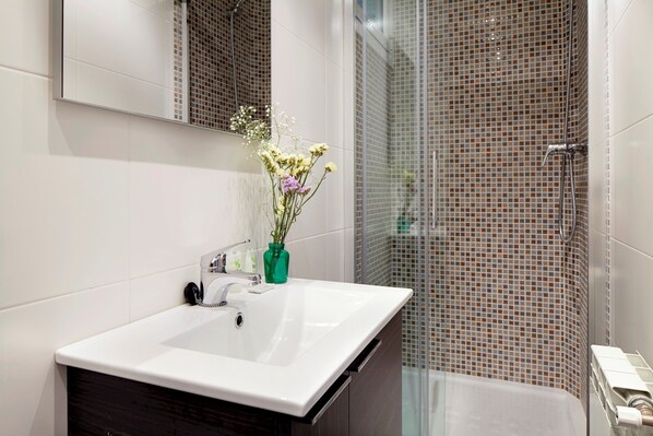 A bathroom with a white sink, a mirror, and a shower with mosaic tiles. - Colon by FeelFree Rentals (San Sebastián)