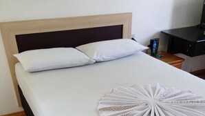 Een keurig opgemaakt bed met een witte spreideken en een decoratieve witte handdoek.