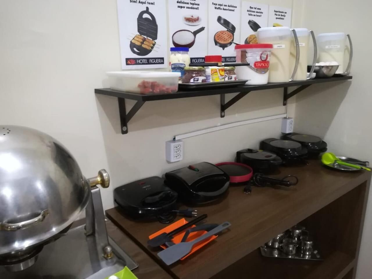 A kitchen with a coffee maker, waffle maker, and various cooking utensils on the counter.