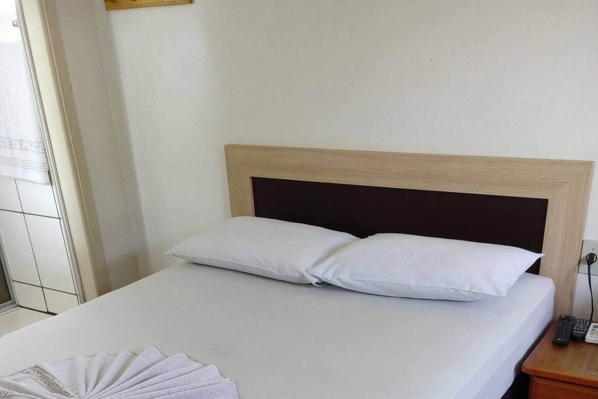 Una cama bien hecha con sábanas blancas y una toalla decorativa.