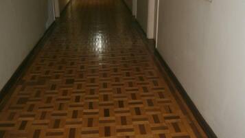 Un pasillo con suelo de madera estampado, puertas a ambos lados y un extintor en la pared izquierda.