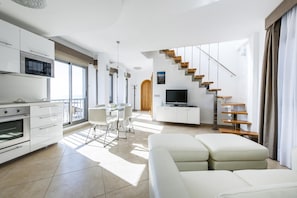 Un appartement moderne comprenant une cuisine, un coin repas, un salon et un escalier.