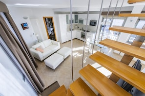 Un appartement moderne comprenant un espace de vie, une kitchenette et un balcon doté de balustrades en bois.