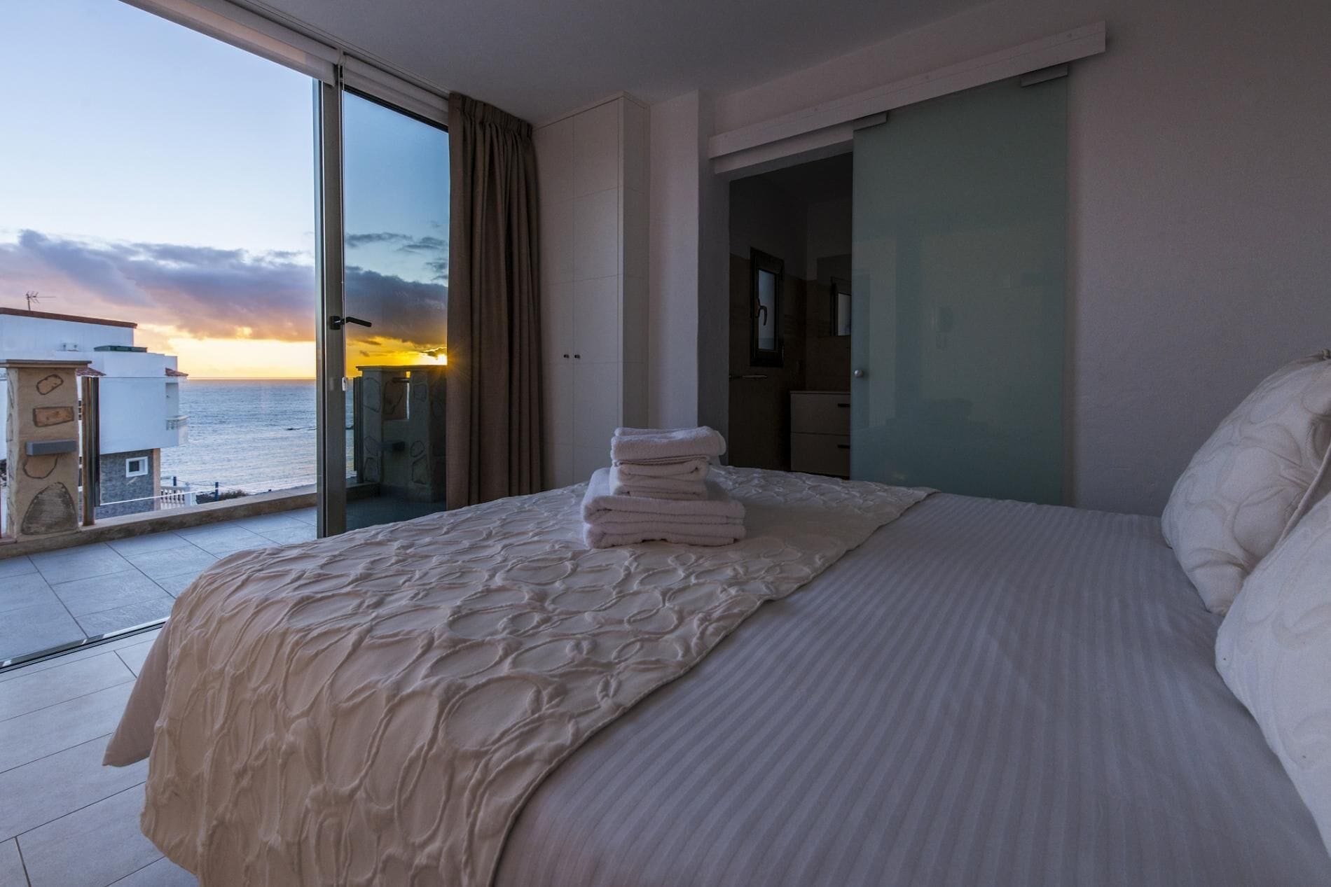 Un cuarto de hotel con una cama grande, vista al mar y un balcón.