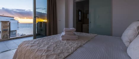 Un cuarto de hotel con una cama grande, vista al mar y un balcón.