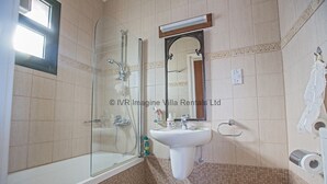 Un bagno con doccia vetrata, lavandino e specchio.