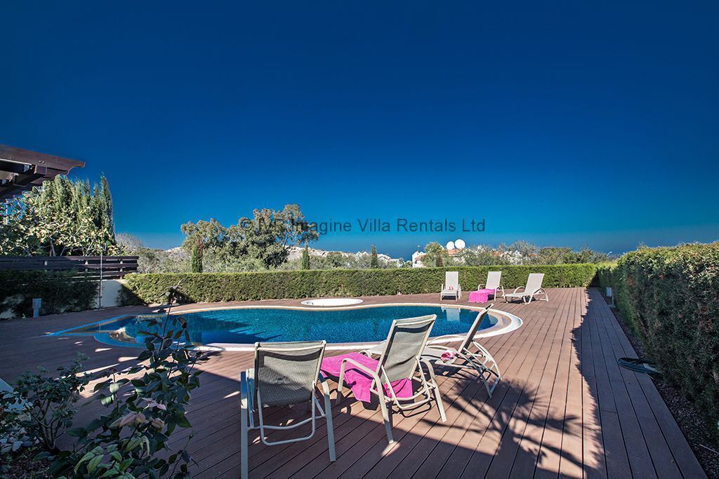 A pool area with lounge chairs and a wooden deck.