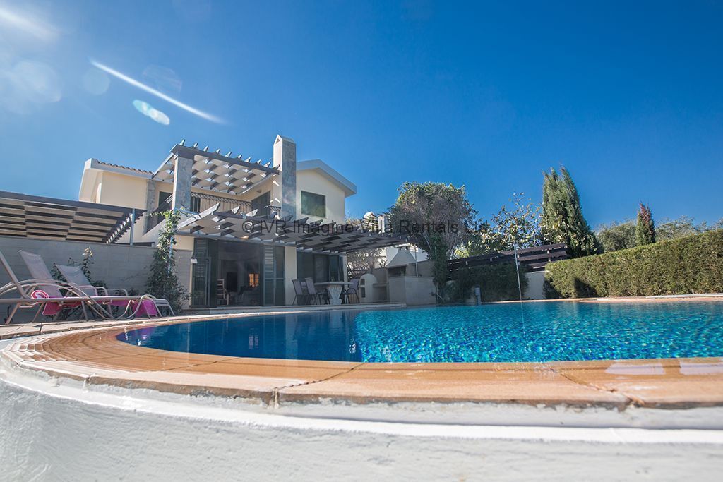 Una piscina con lettini e un edificio sullo sfondo.