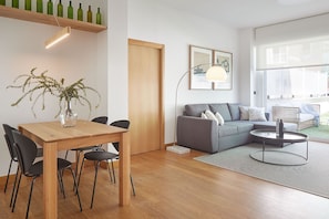 A modern living room with a wooden dining table, grey sofa, and a large window. - Arzak by FeelFree Rentals (San Sebastián)