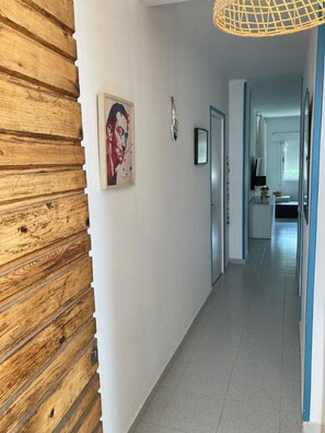 Un couloir avec un mur en bois, un tableau et une porte donnant sur une salle de bain.