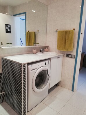 A modern bathroom with a washing machine, sink, and a large mirror. - BOSMAR BOSC 5-A (Pals)