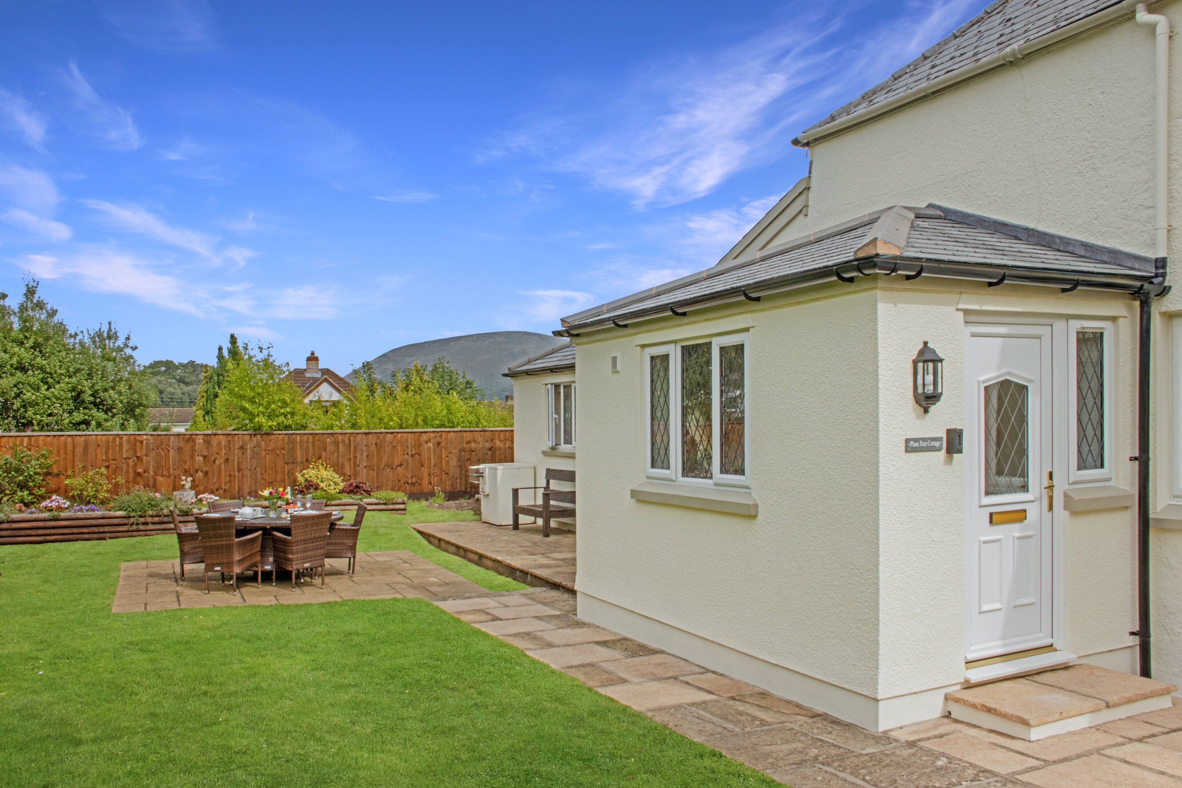 Ein Haus mit Terrasse, einer weißen Tür und einem kleinen Garten.
