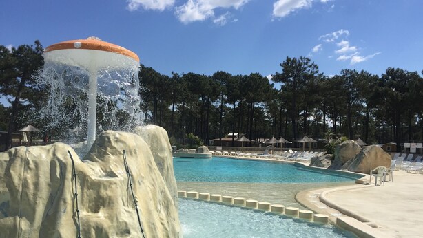 A swimming pool with a water feature, surrounded by lounge chairs and umbrellas. - OCEANBAHIA12 rental luxury 6 pers Club 5 * clim Montalivet Aquitaine  (Vendays-Montalivet)
