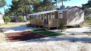 A mobile home with a covered porch and a small front yard. - OCEANBAHIA12 rental luxury 6 pers Club 5 * clim Montalivet Aquitaine  (Vendays-Montalivet)