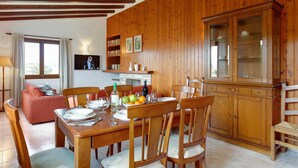 Uma sala de jantar com mobiliário de madeira, uma televisão e um armário com portas de vidro.