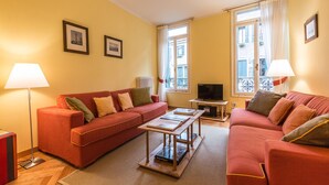 A living room with a red sofa, a coffee table, a TV on a stand, and two lamps. - Ca' Dei Nomboli Canal View (Venice)