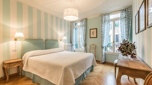 A bedroom with a large bed, two bedside tables, a hanging light fixture, a window with curtains, and a small table with a plant. - Ca' Dei Nomboli Canal View (Venice)