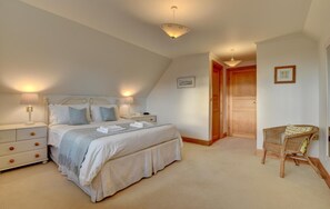 Ein Schlafzimmer mit einem Bett, Nachttischen, einem Sessel und einer Tür.