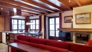 A spacious living area with a wooden ceiling, a fireplace, a television, and a red sofa. - Val de Ruda 31 by FeelFree Rentals (Baqueira)