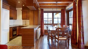 A kitchen with wooden cabinets, a central island, and a dining area with a table and chairs. - Val de Ruda 31 by FeelFree Rentals (Baqueira)
