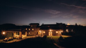 A large stone house with multiple rooms and a well-lit outdoor area at night.