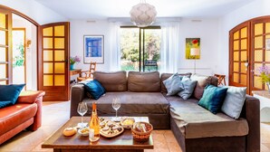 A living room with a brown leather sofa, a wooden coffee table with food and drinks, and a large window with curtains. - Villa Nyons Drôme provençale private heated pool Wifi Bbq (Nyons)