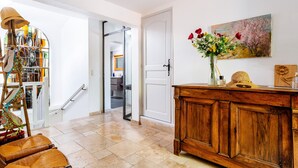 A well-lit hallway with a wooden cabinet, a vase with flowers, and a painting on the wall. - Villa Nyons Drôme provençale private heated pool Wifi Bbq (Nyons)