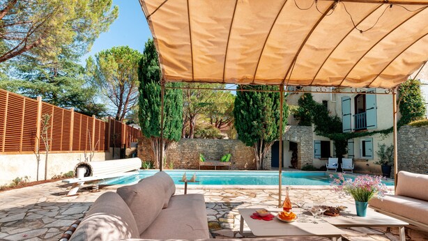 A poolside area with a covered seating area, stone flooring, and a view of a pool and stone wall. - Villa Nyons Drôme provençale private heated pool Wifi Bbq (Nyons)