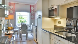 Ett modernt kök med inbyggd mikrovågsugn, diskho i rostfritt stål och en matplats med bord och stolar.