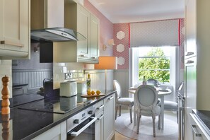 A modern kitchen with a central island, built-in appliances, and a dining area with a view of greenery.