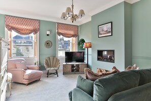A living room with a sofa, armchair, TV, and decorative items.