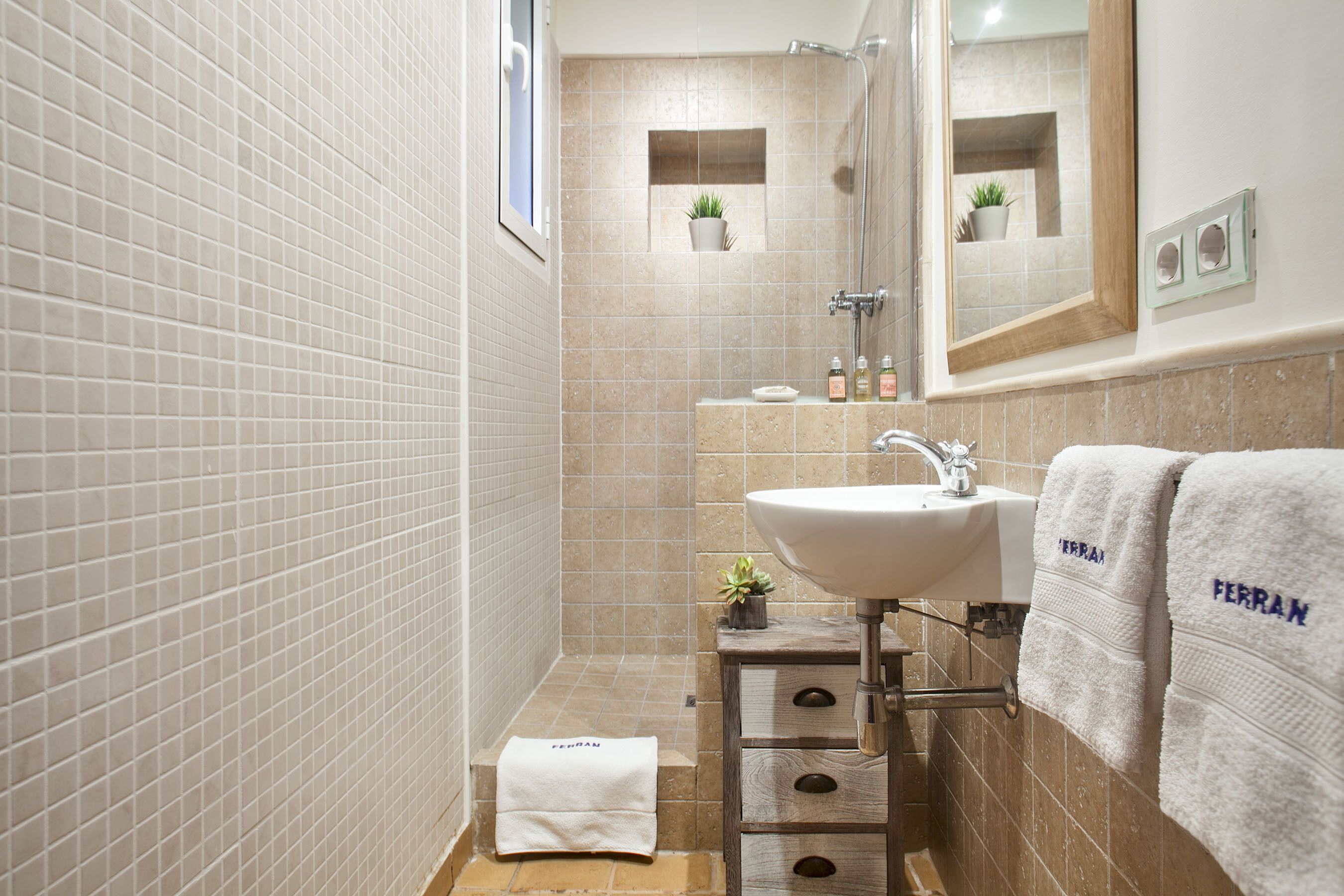 Une salle de bain avec un sol carrelé, un lavabo, un miroir et un porte-serviettes.