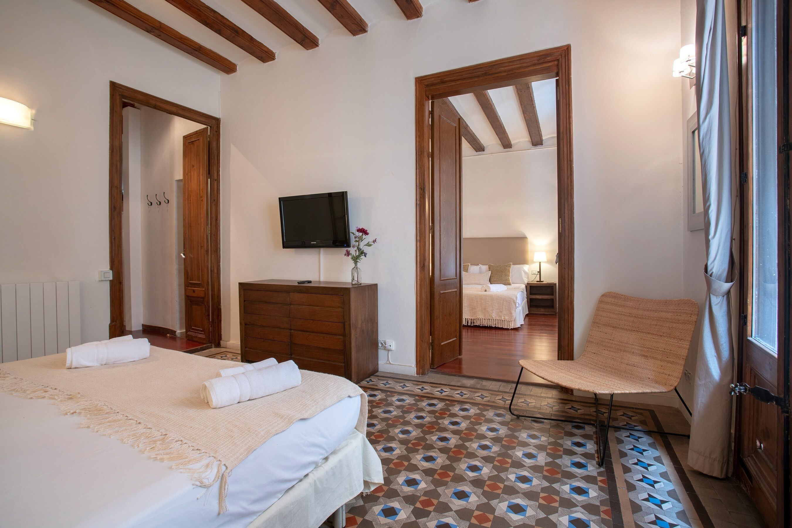 Une chambre à coucher comprenant un lit, une chaise, une commode, un téléviseur et un sol à motifs.
