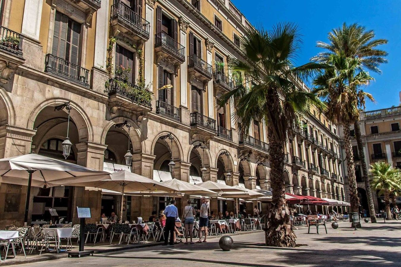 Un edificio histórico con mesas al aire libre y palmeras.