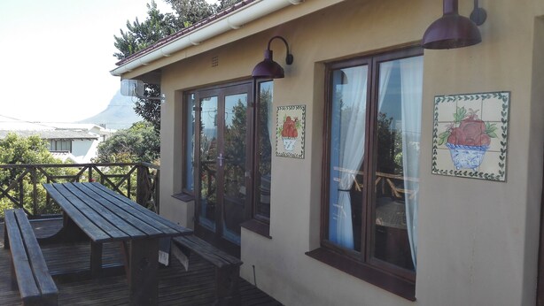 A wooden deck with a bench, a building with large windows, and a mountain in the background.