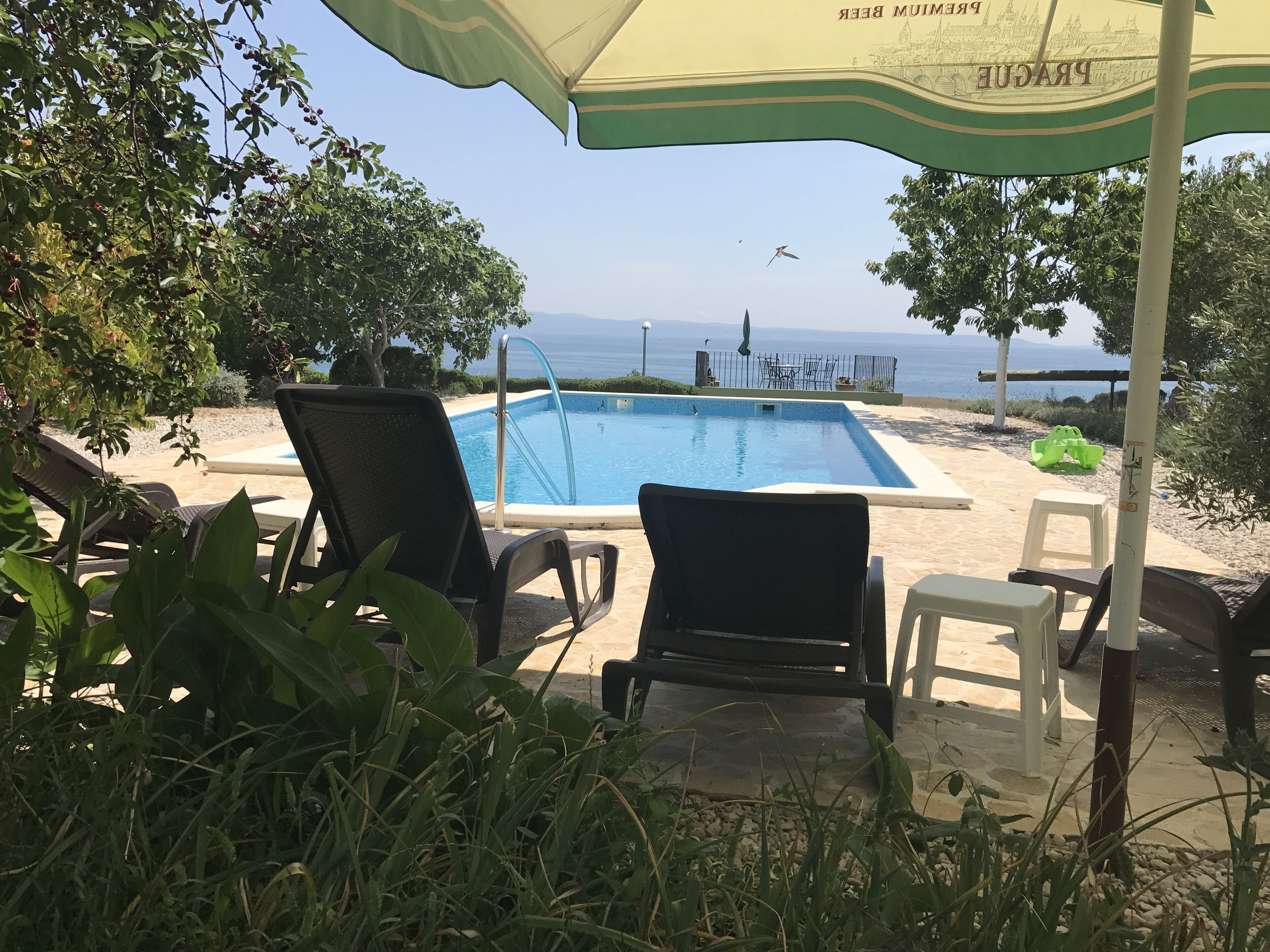 Área da piscina com espreguiçadeiras, piscina e vista para o mar.