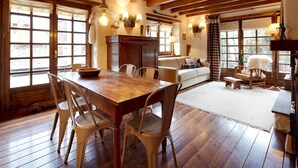 A wooden dining table with chairs, a sofa, and a fireplace in a cozy room with wooden floors and large windows. - Solei by FeelFree Rentals (Garòs)