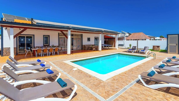 A poolside area with lounge chairs and a dining setup. - Villa Susi - Five Bedroom Villa, Sleeps 10 (Fuerteventura)
