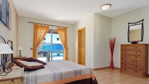 A bedroom with a bed, a dresser, a mirror, and a window with curtains.