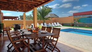 An outdoor dining area with a pool and lounge chairs.