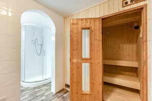A modern bathroom with a glass shower enclosure, wooden sauna, and a tiled floor. - 3 Bed in Clifton Court (oc-fl8) (Croyde)