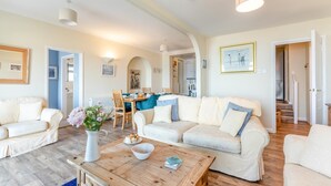 A spacious living room with a large sofa, a coffee table, and a dining area with chairs and a table. - 3 Bed in Clifton Court (oc-fl8) (Croyde)
