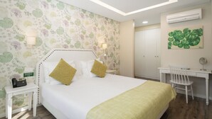 Une chambre d’hôtel équipée d’un lit, d’une table de chevet, d’un bureau, d’une chaise et d’une affiche indiquant le numéro de téléphone à contacter en cas d’urgence.